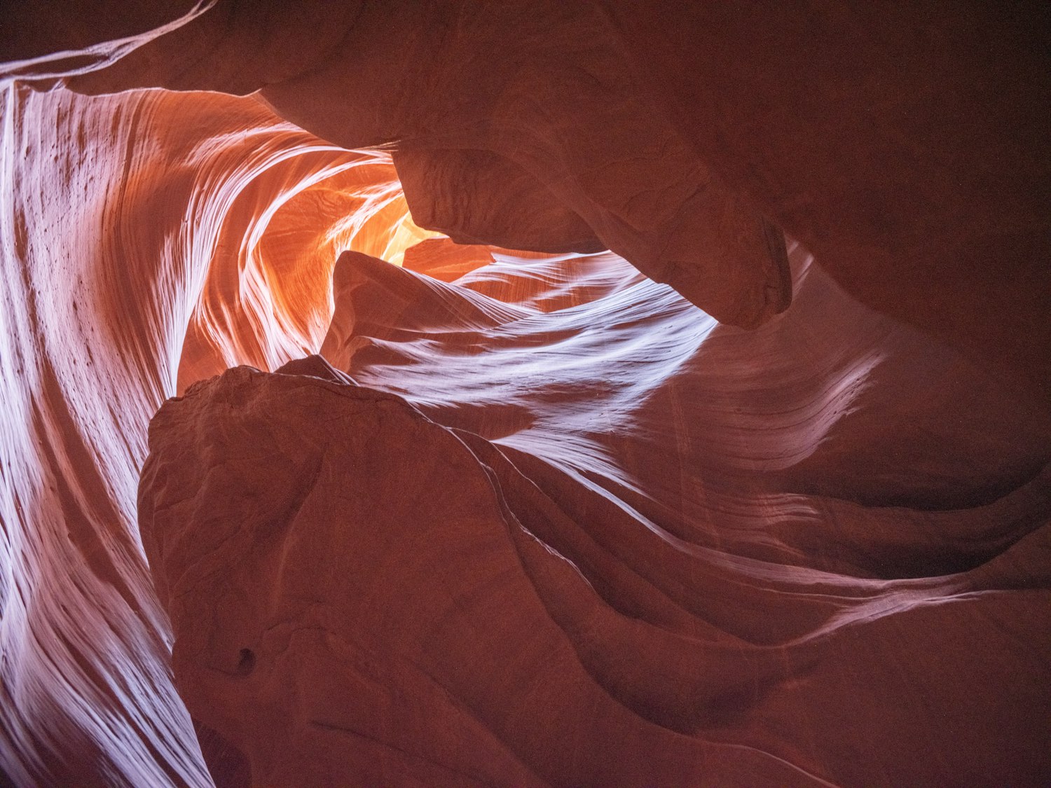 Swirling sandstone walls of a slot canyon lit in warm orange tones