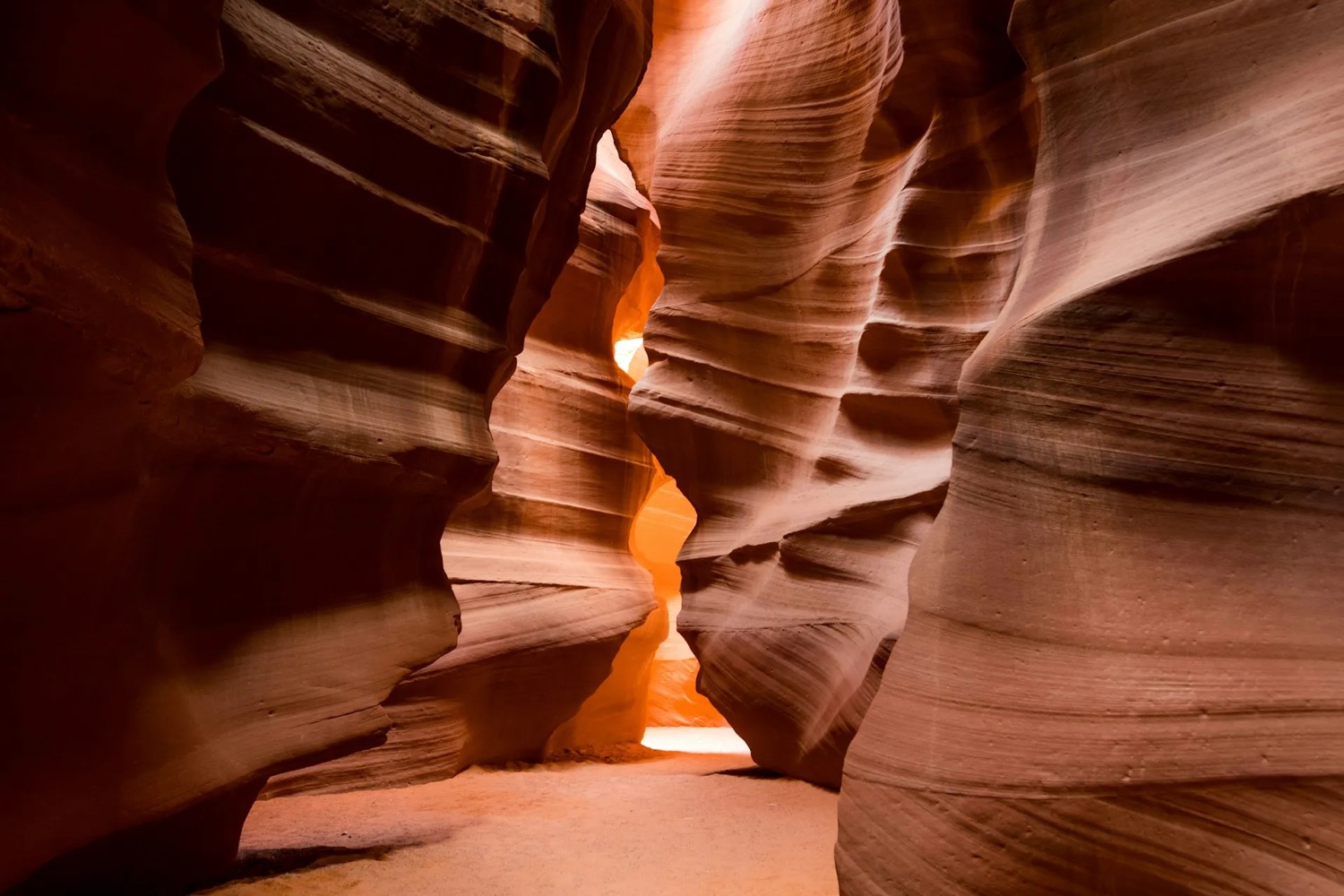 A warmly lit sandstone canyon corridor with sculpted rock walls