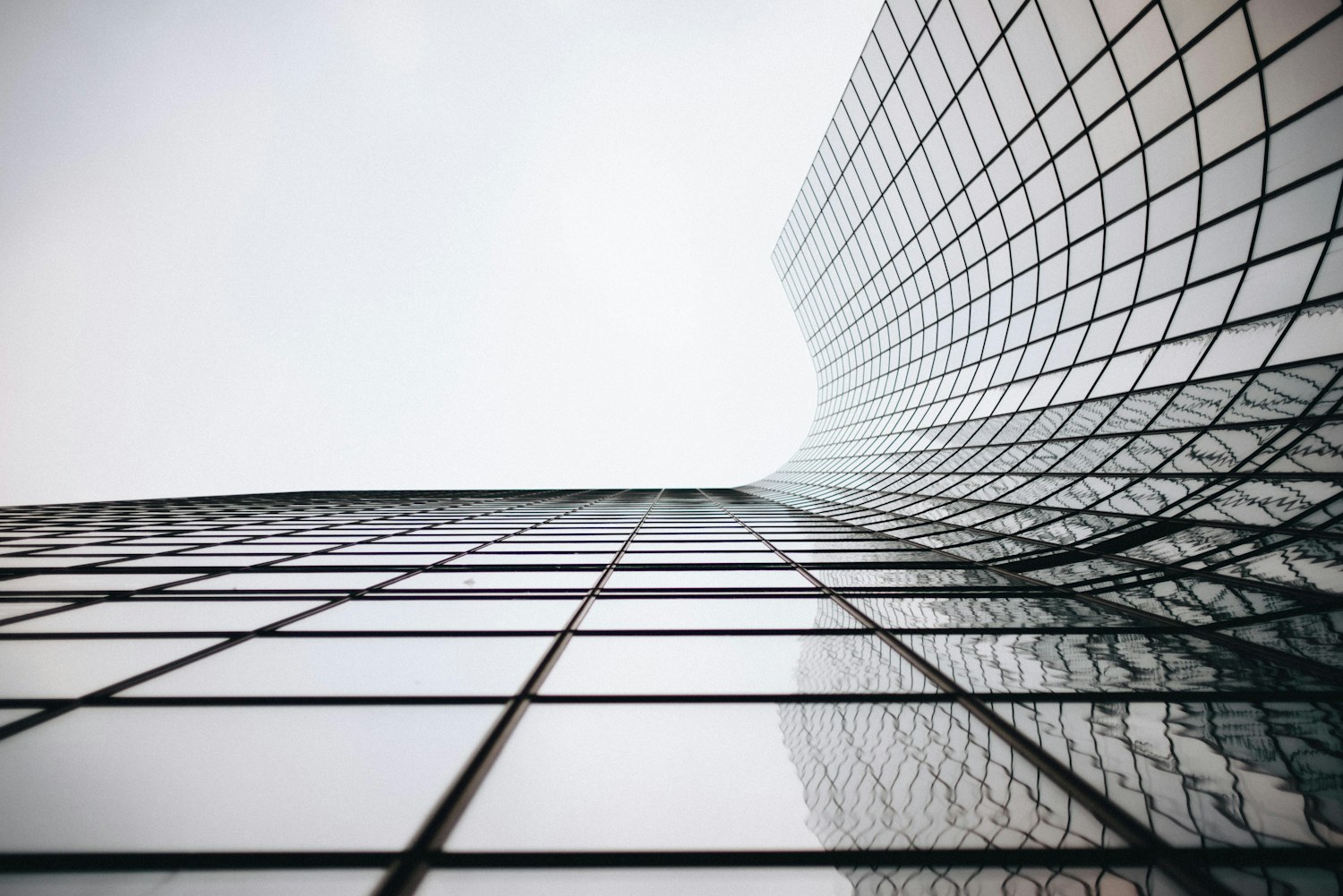 A curved glass and steel building facade viewed from below