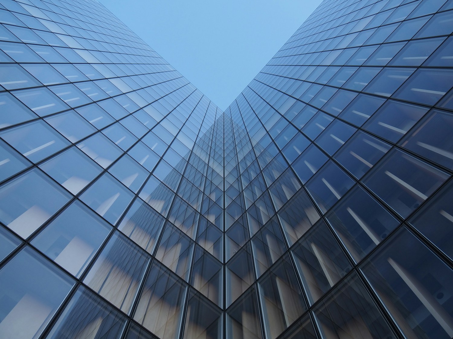 A glass office tower viewed from below against the sky