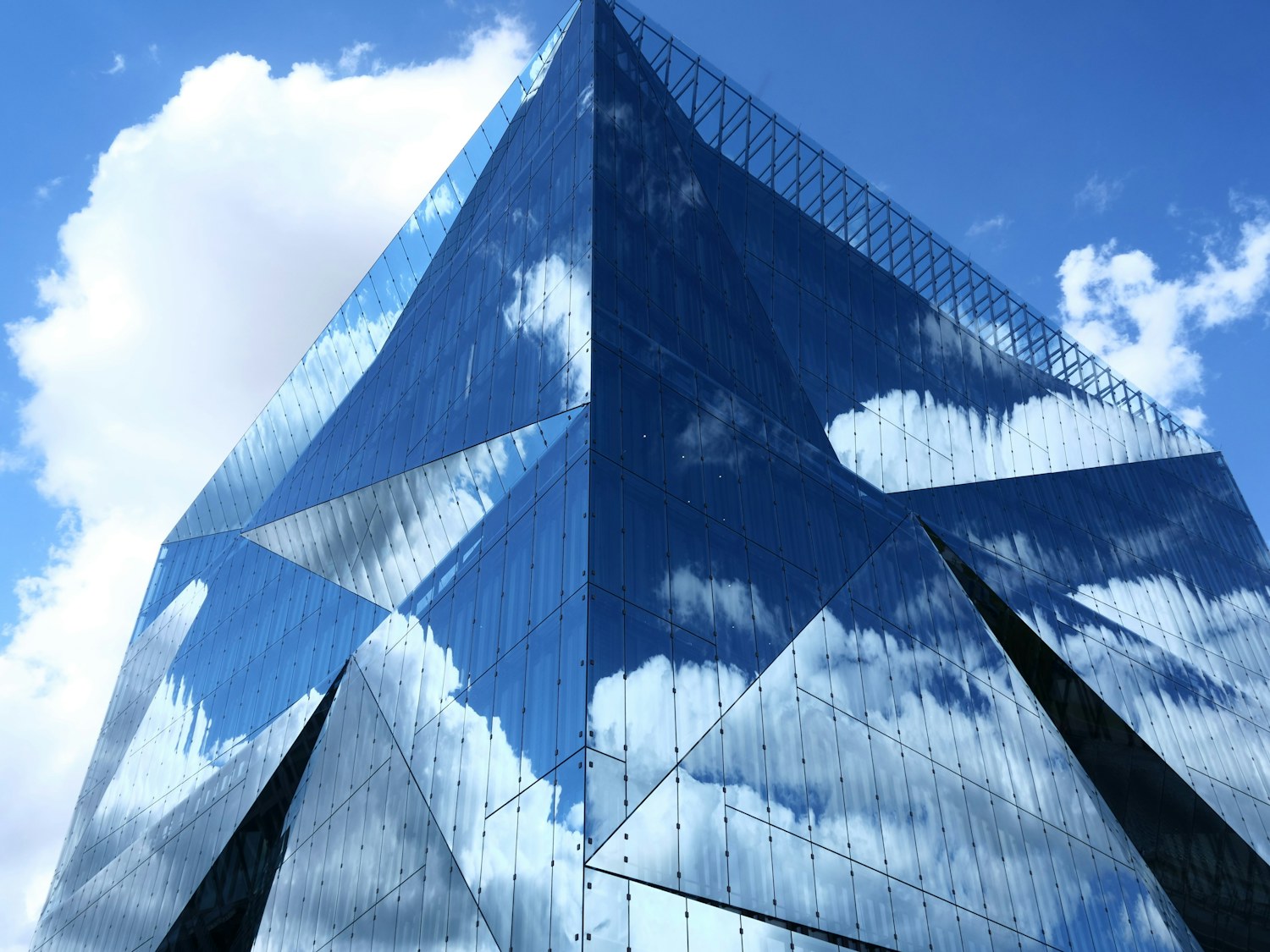 A glass building facade reflecting the sky in fragmented panels
